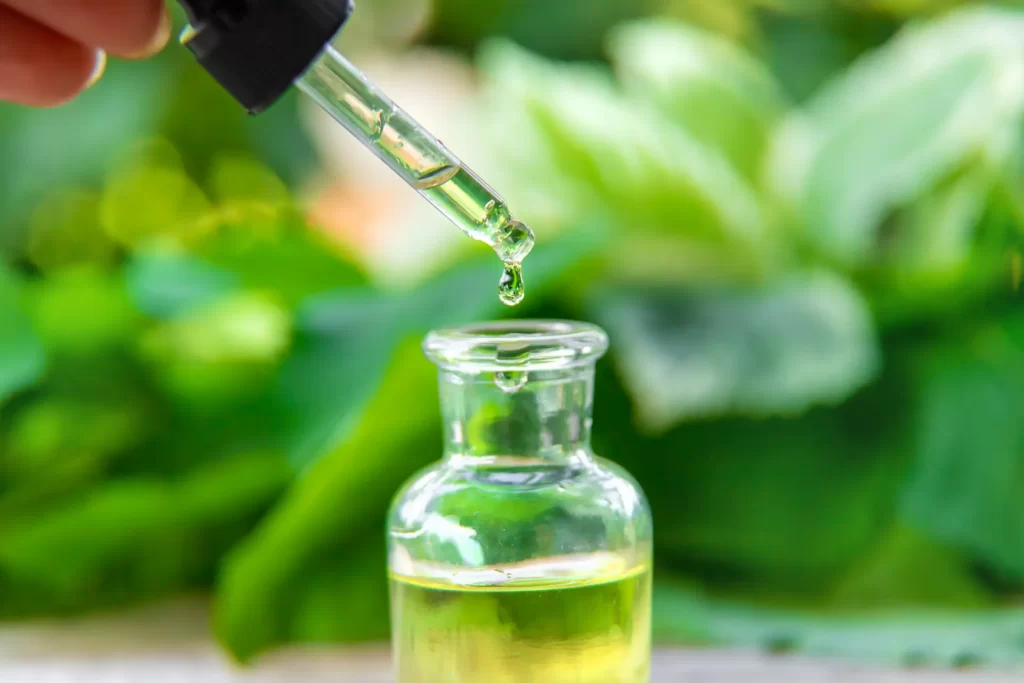 aceite de copaiba botella de vidrio con gotero sobre fondo verde