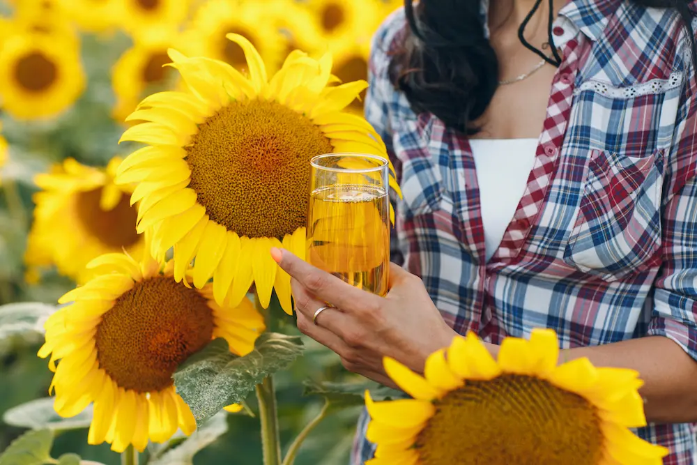 aceite de girasol mujer con botella en campo de flores