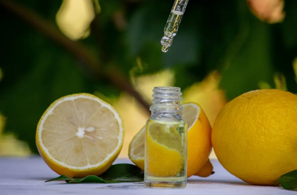 aceite de limon botellita con aceite y limones partidos y enteros sobre fonde de naturaleza