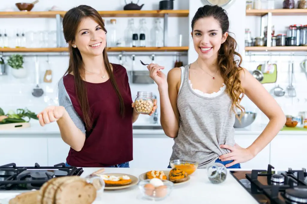 Dos mujeres joven felices posando con un bowl de garbanzos en la mano
