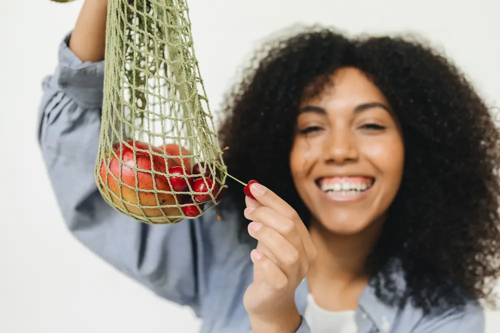 fruta con fibra mujer joven sonriendo mostrando bolsa de malla