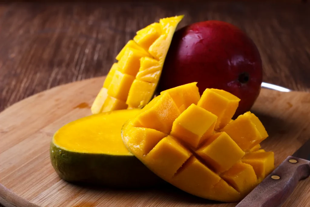 mango fruta entera y en cuadraditos sobre tabla de picar