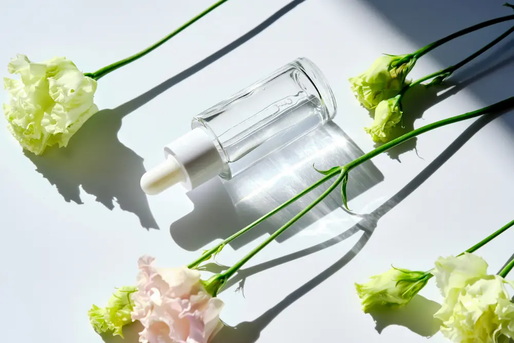 vitamina b3 botella con liquido transparente y flores blancas