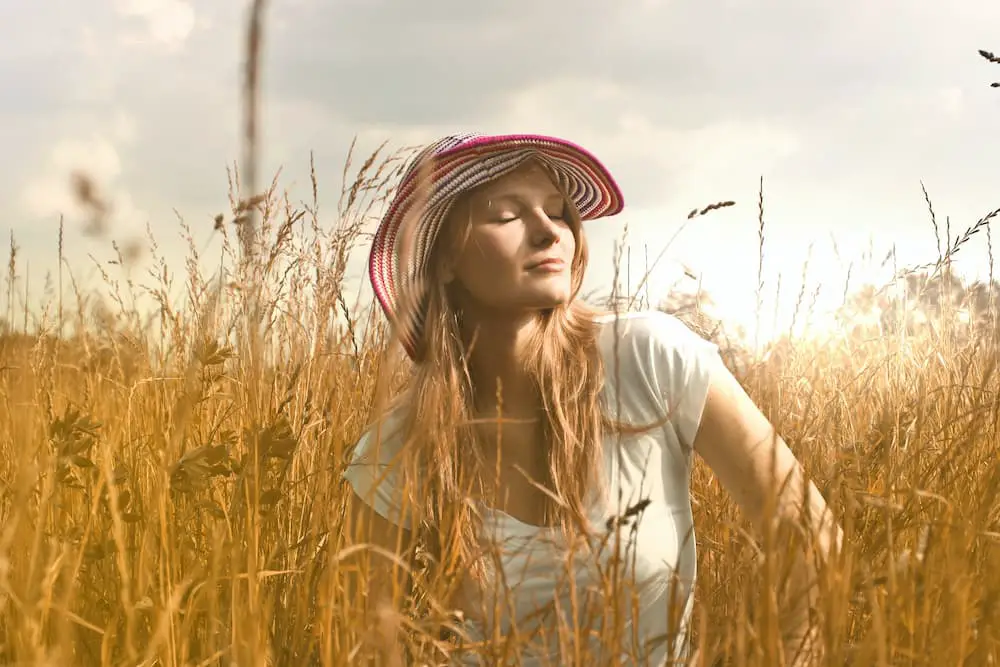 vitamina d mujer con sombrero tomando el sol en el campo